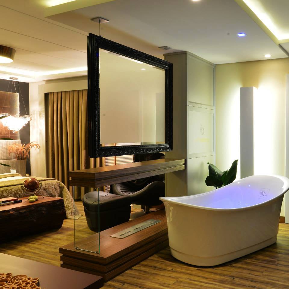 Imagem de um quarto com banheira, onde há um painel separando a cama da banheira 