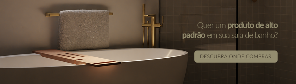 imagem de uma banheira de imersão dentro de um banheiro, a banheira possui monocomando dourado e um porta toalhas atrás da banheira. 