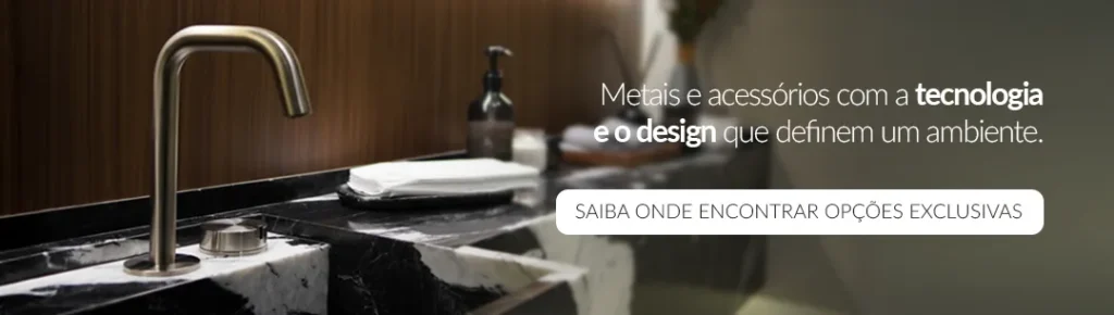 Banheiros modernos Doka: banner com bica e acionamento da linha Quantum em aço inox escovado sobre bancada em mármore preto com veios brancos, ao lado de dispenser de sabonete, com painel de madeira ao fundo e texto 'Metais e acessórios com a tecnologia e o design que definem um ambiente'